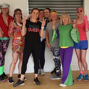 An image of Claire with her students smiling and in fancy dress
